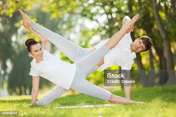 Couples Yoga Man And Woman Doing Exercises In The Park Stock Photo - Download Image Now