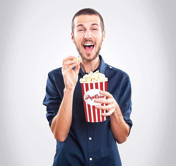 istock Young happy man watching movie and holding popcorn 451624077
