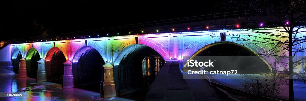 Rainbow Bridge, Night Photography Panoramic Rainbow bridge illuminated by colored lights and photographed at night with beautiful reflections in the Conemaugh River below, Johnstown, PA, USA. Pennsylvania Stock Photo