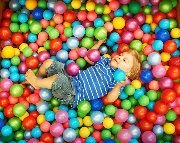 istock Happy child playing with colorful plastic balls 451626961