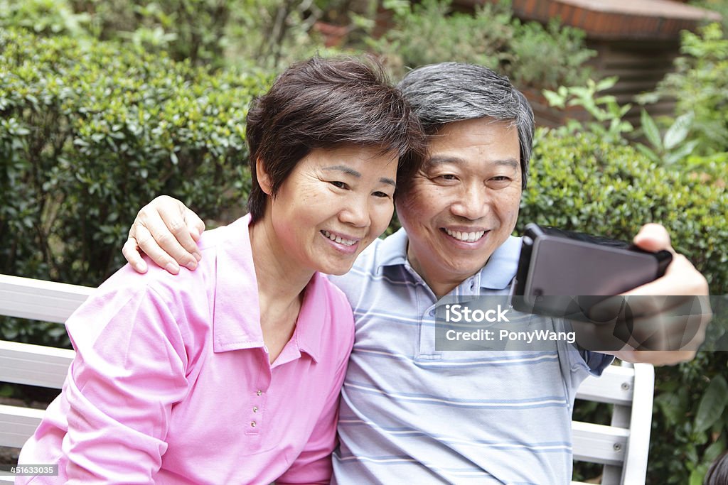 Happy elderly seniors couple smile using smart phone Happy elderly seniors couple smile using smart phone, asian family Active Seniors Stock Photo