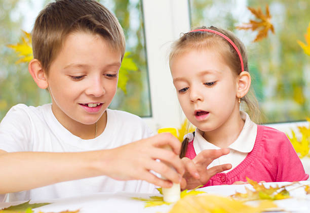 istock A little boy and girl doing arts and crafts using leaves  451645531