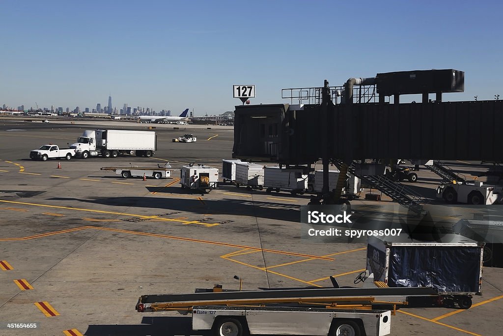 Newark Airport runway area Newark International Airport runway area with baggage carts, metal tube and trucks & airplane on a background on a clear blue sky. Airplane Stock Photo