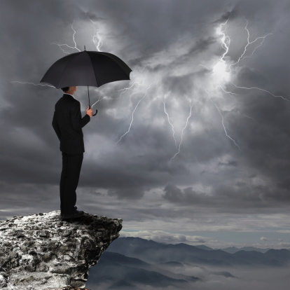 Business Man with an umbrella look rainstorm clouds ,  concept for business and insurance