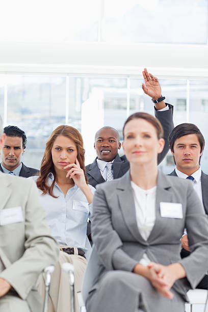 istock Smiling businessman raising his hand for attention while sitting 451787033