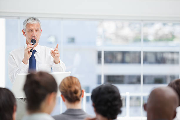 istock Mature businessman using a microphone for talking to his colleagues 451787625