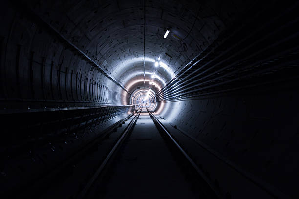 Long dark tunnel with tracks with a light at the end