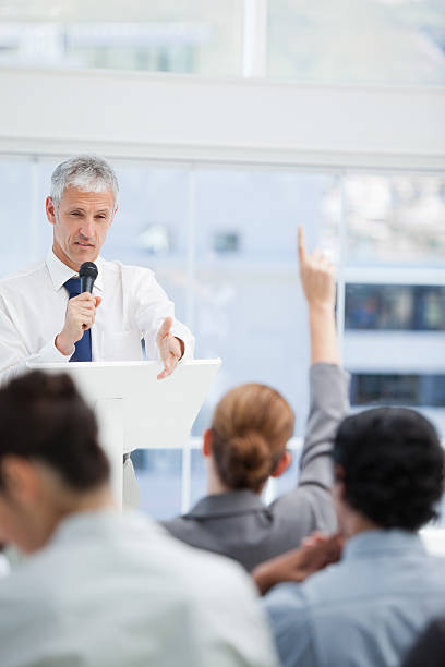 istock Businessman holding a microphone and gesturing to his colleague 451800955