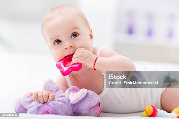 Bebé Masticar Un Primer Juguete En La Cama Foto de stock y más banco de imágenes de Bebé - Bebé, Mordedor, Juguete