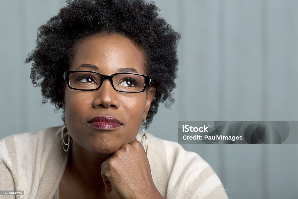 african woman wearing glasses with a hand on chin A woman of african decent  wearing glasses with hand on chin looking pensive Adult Stock Photo