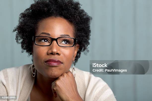 African Woman Wearing Glasses With A Hand On Chin Stock Photo - Download Image Now - Adult, African Ethnicity, African-American Ethnicity