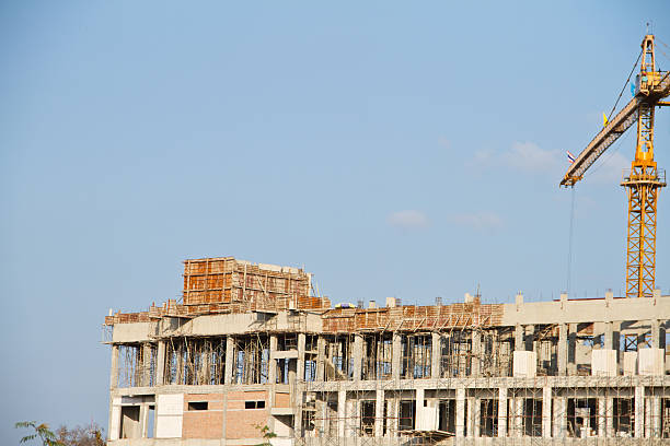 istock Crane and workers at construction site against blue sky. Thailand 451808267