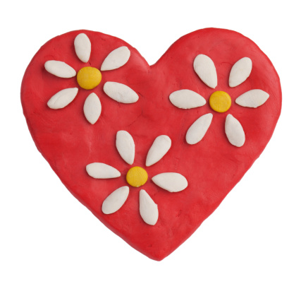 Red plasticine heart with daisies on a white background