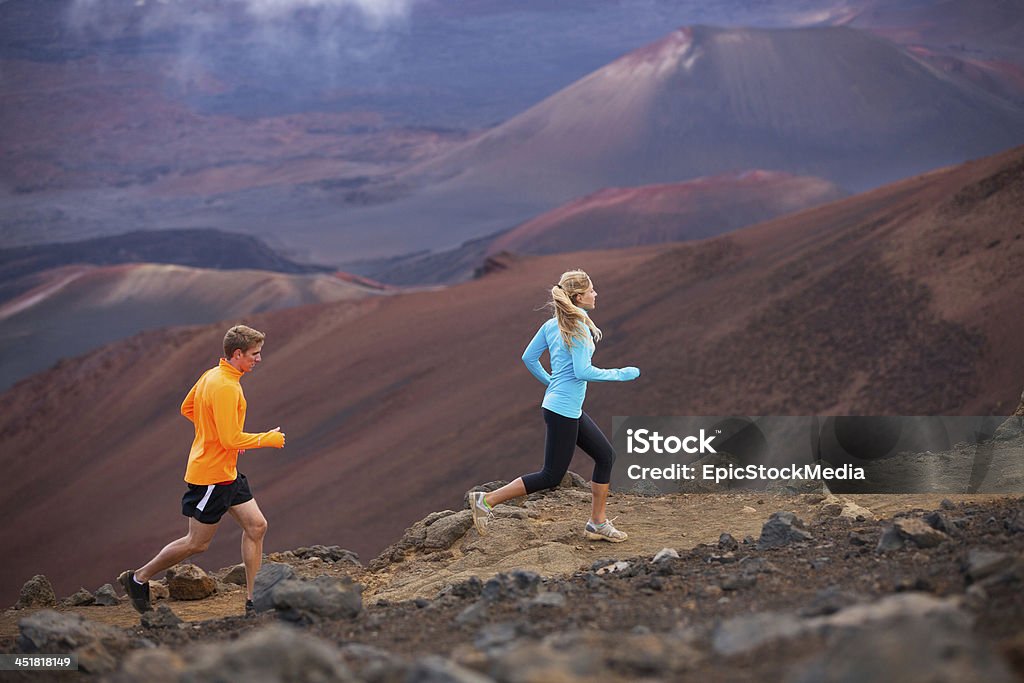 Active sport couple running on mountain ridge trail Fitness sport couple jogging outside, training together outdoors. Running on amazing trail at sunset, Dramatic beautiful volcano landscape Active Lifestyle Stock Photo