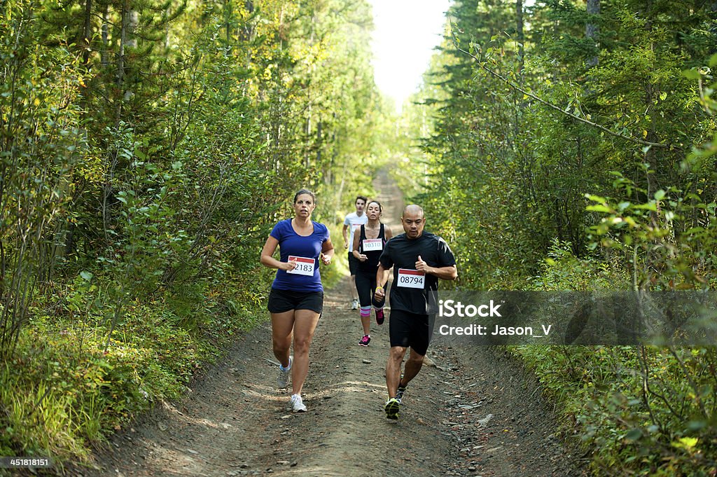 Path Race A group of 4 people running a path race in the forest.  Focus on the first 2 runners Active Lifestyle Stock Photo