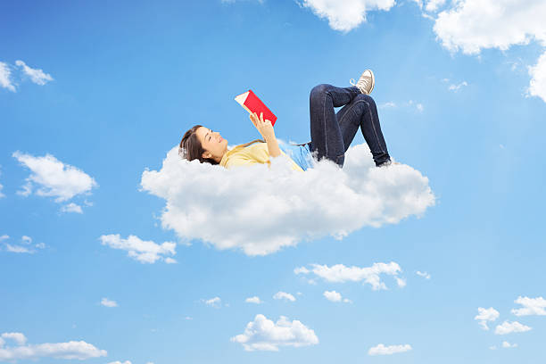 istock Relaxed female reading a novel and lying on clouds 451818827