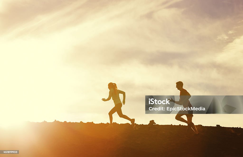 Man and woman runing together into sunset Silhouette of man and woman running jogging together into sunset, Wellness fitness concept Active Lifestyle Stock Photo