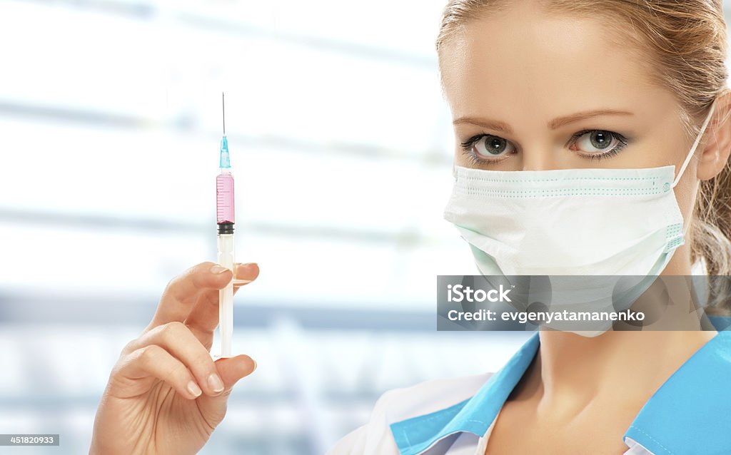 Medico donna in una maschera con la siringa Vaccino - Foto stock royalty-free di Accudire