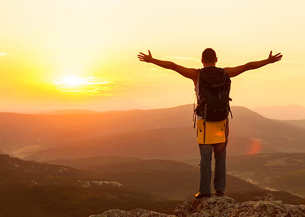 istock guy in the mountains at sunset. 451827881