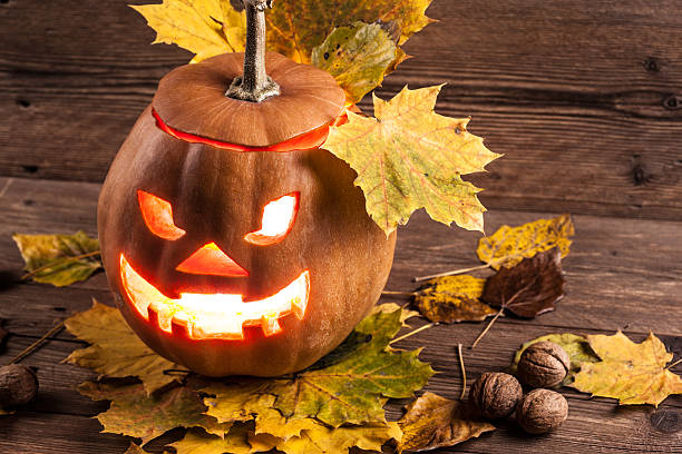 istock jack-o-lantern with leaves on wooden background 451829187