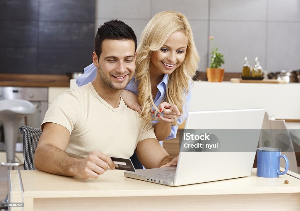 Happy couple shopping online Happy young couple shopping online, using laptop computer and credit card, smiling.. 20-24 Years Stock Photo