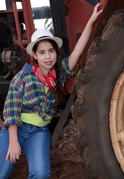 menina em roupas ocidental em um tractor - fashion women denim farm imagens e fotografias de stock