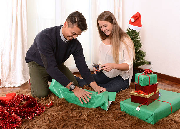 istock Young Happy Couple wrapping Christmas presents 451844221