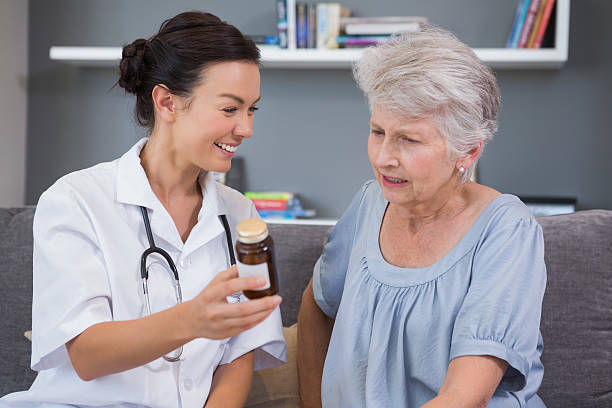 istock Home nurse showing medication to her mature patient 451856563