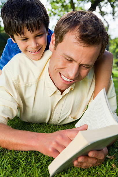 istock Smiling father reading a book with his son 451860627