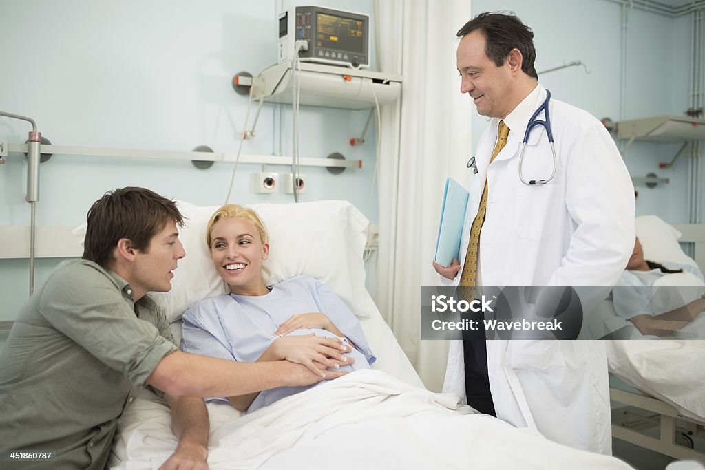 Obstetrician talking with a patient and her husband - Стоковые фото 20-29 лет роялти-фри
