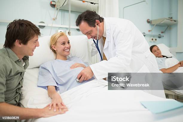 Doctor Hombre Usando Un Estetoscopio A Su Sonriente Mujer Embarazada Foto de stock y más banco de imágenes de 20 a 29 años