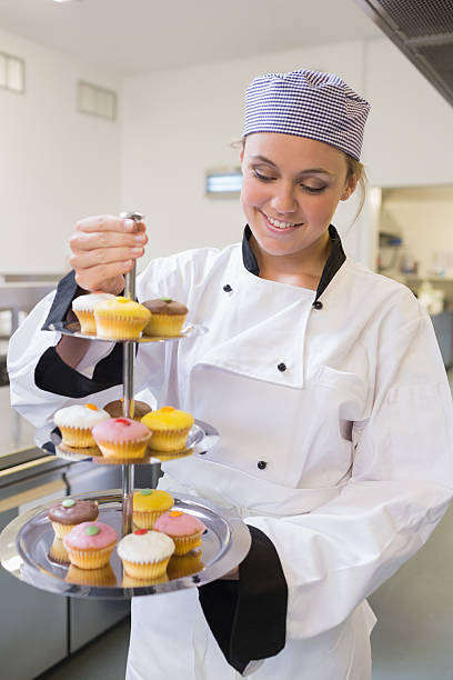 istock Smiling woman holding a three tiered cake tray 451861083