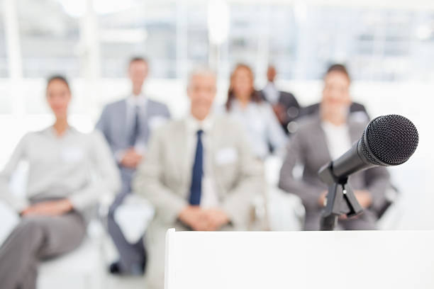 istock Microphone on a podium in front of business team 451861473