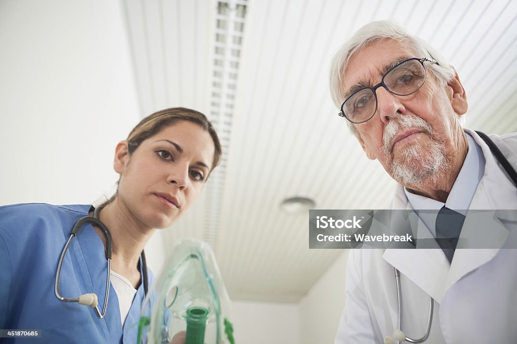 Nurse and a doctor putting an oxygen mask on Nurse and a doctor putting an oxygen mask on in a hospital hallway 20-29 Years Stock Photo