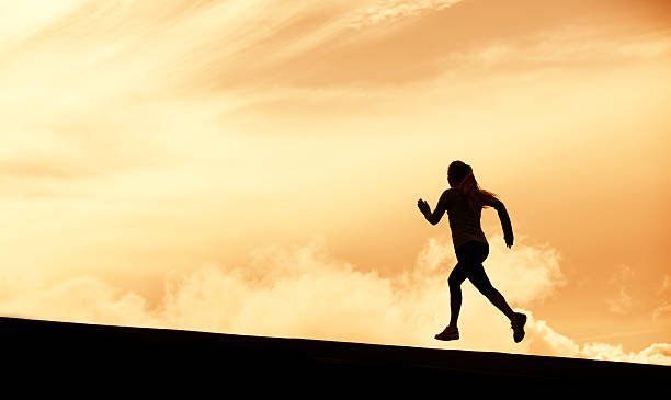 istock Female runner silhouette, running into sunset 451877121