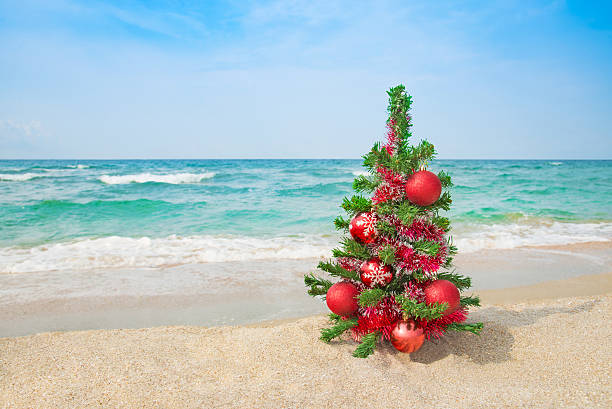 istock Christmas tree with red decorations on the sea beach. 451877967