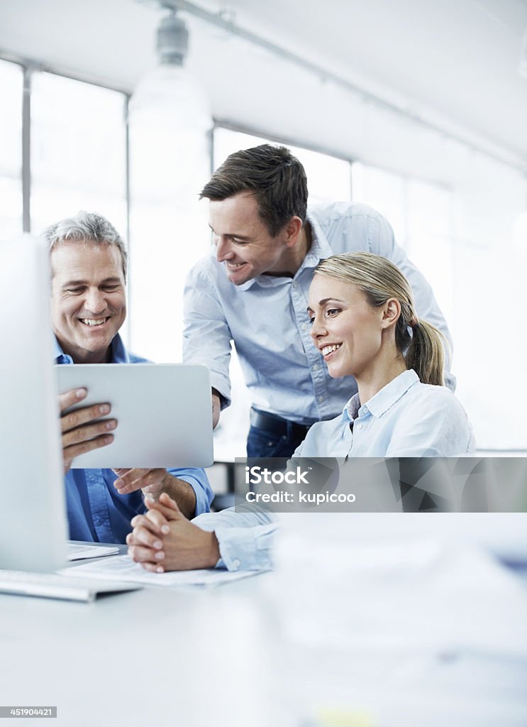 This tablet is so useful! Three businesspeople looking at a digital tablet while working together in their office Office Stock Photo