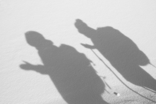 Two backpackers cast their shadow over Snow-covered ground.