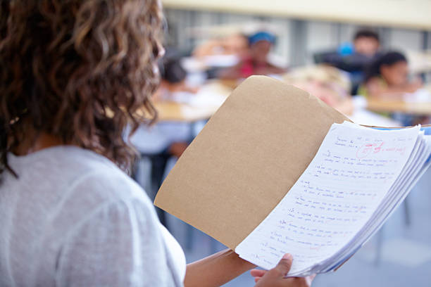 Ready to announce the marks An over the shoulder view of a teacher reading out student marks report card stock pictures, royalty-free photos & images