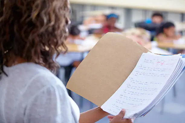 An over the shoulder view of a teacher reading out student marks