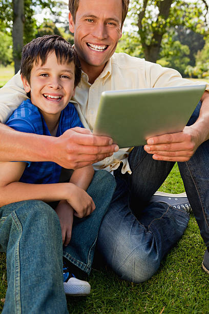 istock Smiling little boy sitting in a park with his father 451963117