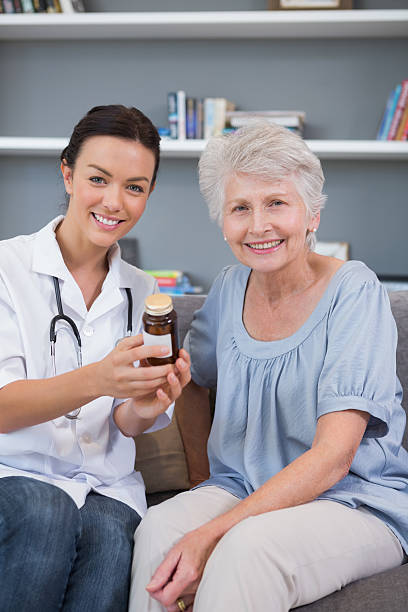 istock Home nurse holding medication with her mature patient 451963981