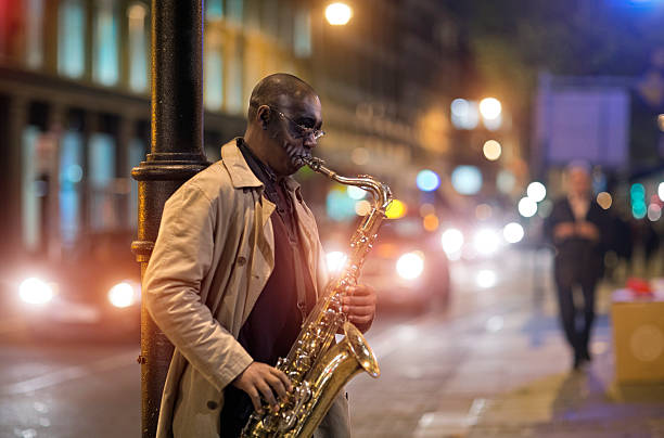 schwarze street-musiker spielen am saxophon in den abend - street musician stock-fotos und bilder