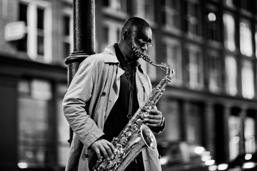 Black Street Musician in London, UK, playing on saxophone in the evening,
