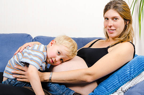 istock Smiling pregnant mother with her little boy on sofa 451982937