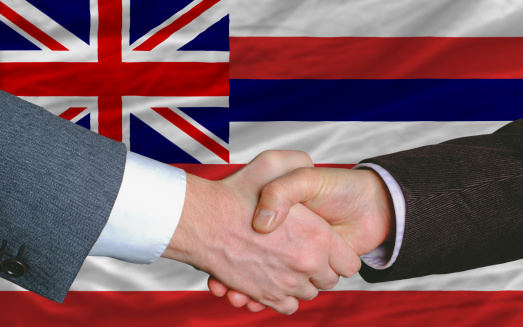 two businessmen shaking hands after good business investment agreement in front US state flag of hawaii