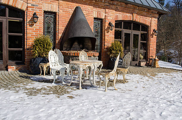 retro decorative outdoor table and chairs near restaurant fireplace building between snow in winter.