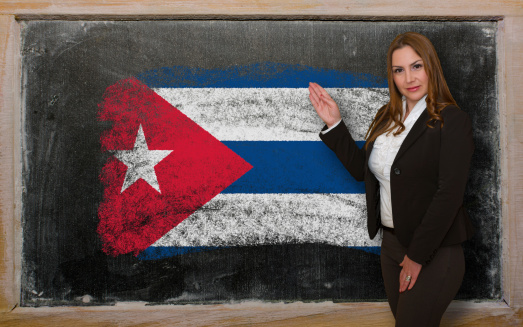 Successful, beautiful and confident woman showing flag of Cuba on blackboard for marketing research, presentation and tourist advertising