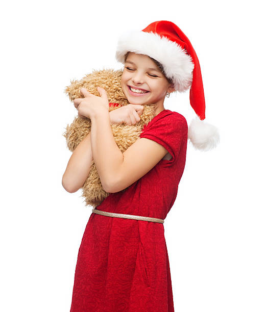 istock smiling girl in santa helper hat with teddy bear 451991657