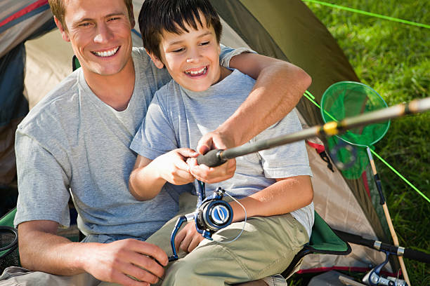 istock Smiling man sitting with his son while fishing 451993297
